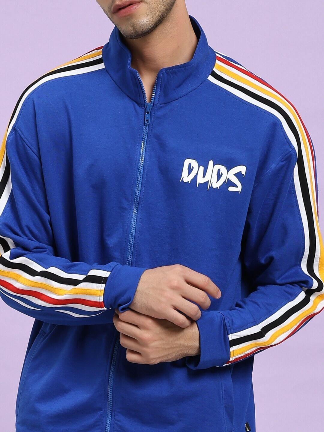 Blue tracksuit with colorful stripes on sleeves against a light purple background