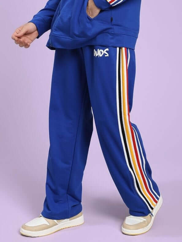 MODERN EDGE MULTI-STRIPE JOGGER ROYAL BLUE Person wearing a blue tracksuit with colorful stripes on a light purple background