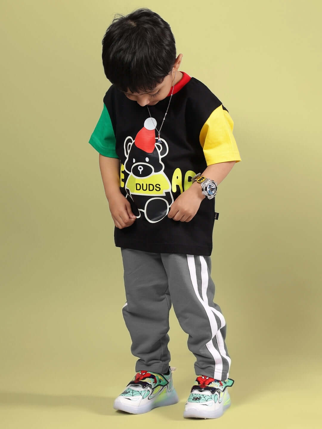 Child wearing DUDS black and grey co-ord set for boys and girls, featuring colorful bear graphic t-shirt and striped pants.