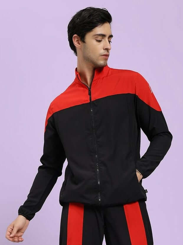 POWER BLOCK RELAXED FIT JACKET BLACK RED Person wearing a black and red tracksuit against a light purple background