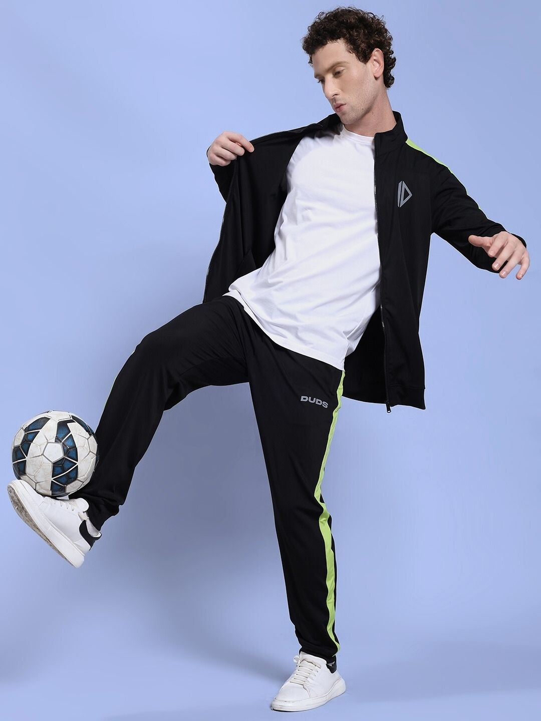 Man wearing HIGH PERFORMANCE CO-ORD SET BLACK while playing soccer indoors, showcasing urban athleisure fashion and comfort.
