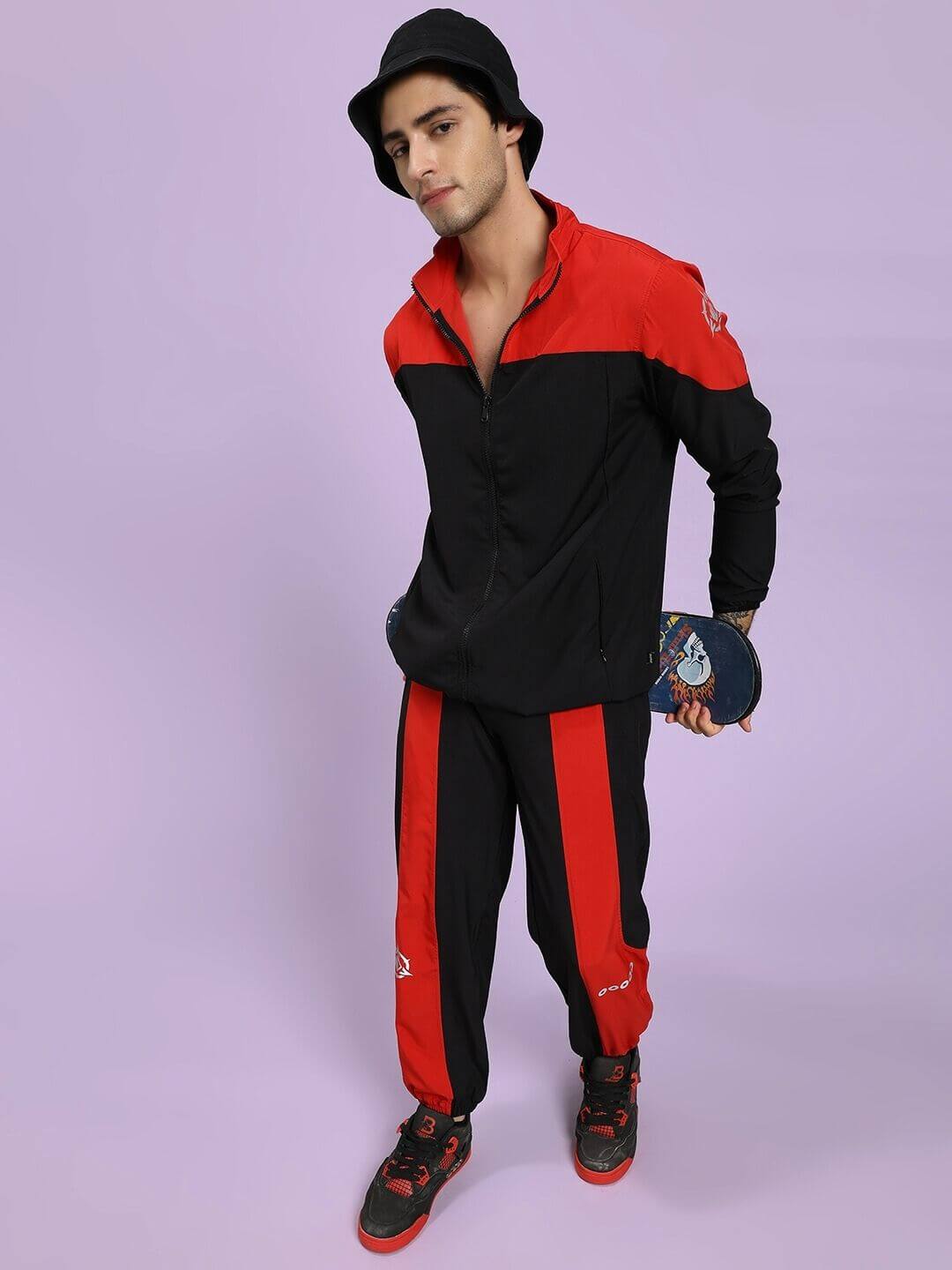 POWER BLOCK CO-ORD SET BLACK RED Person wearing a black and red tracksuit holding a paddle on a light purple background