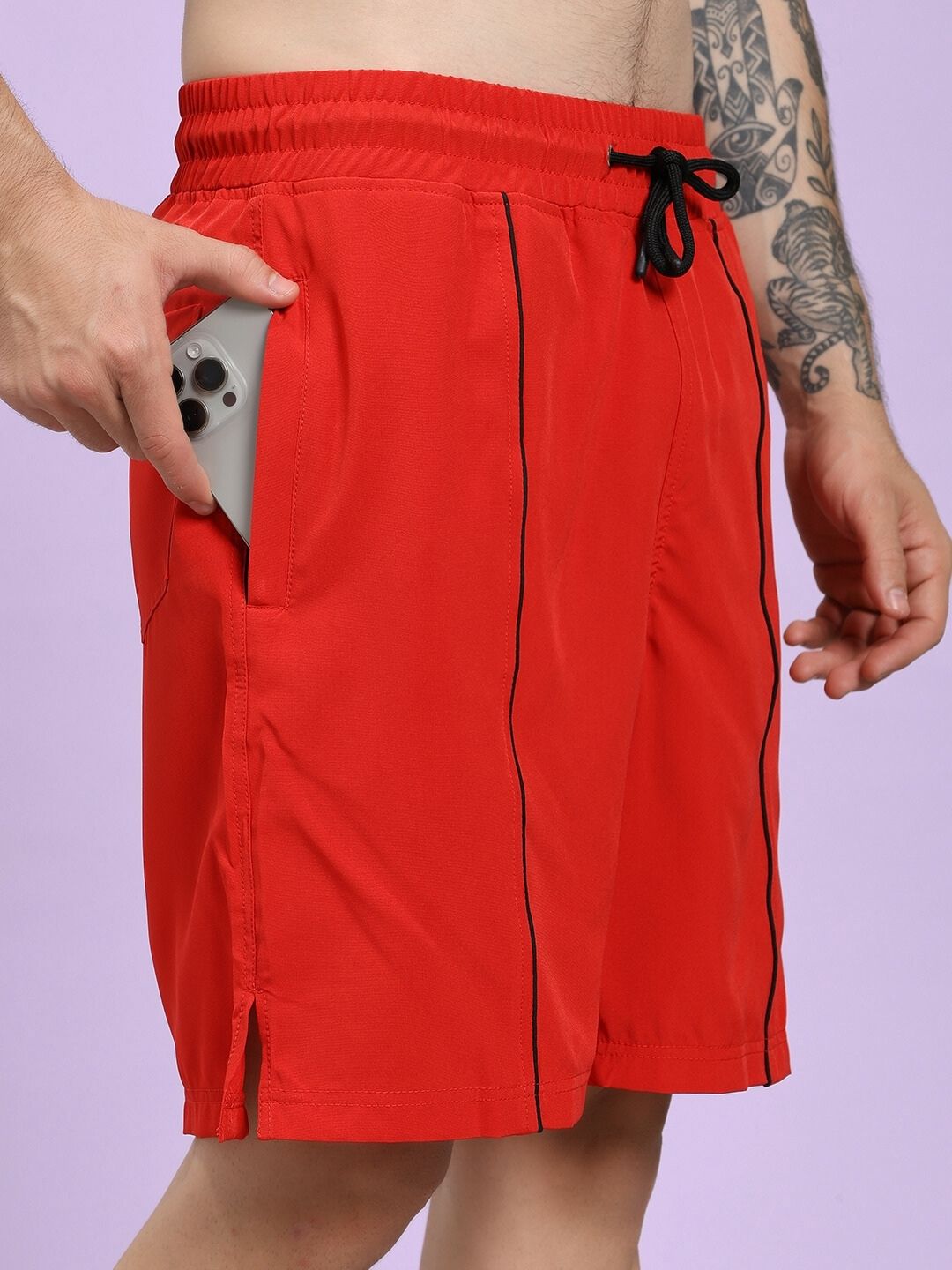 Red shorts with black trim worn by a person on a light purple background