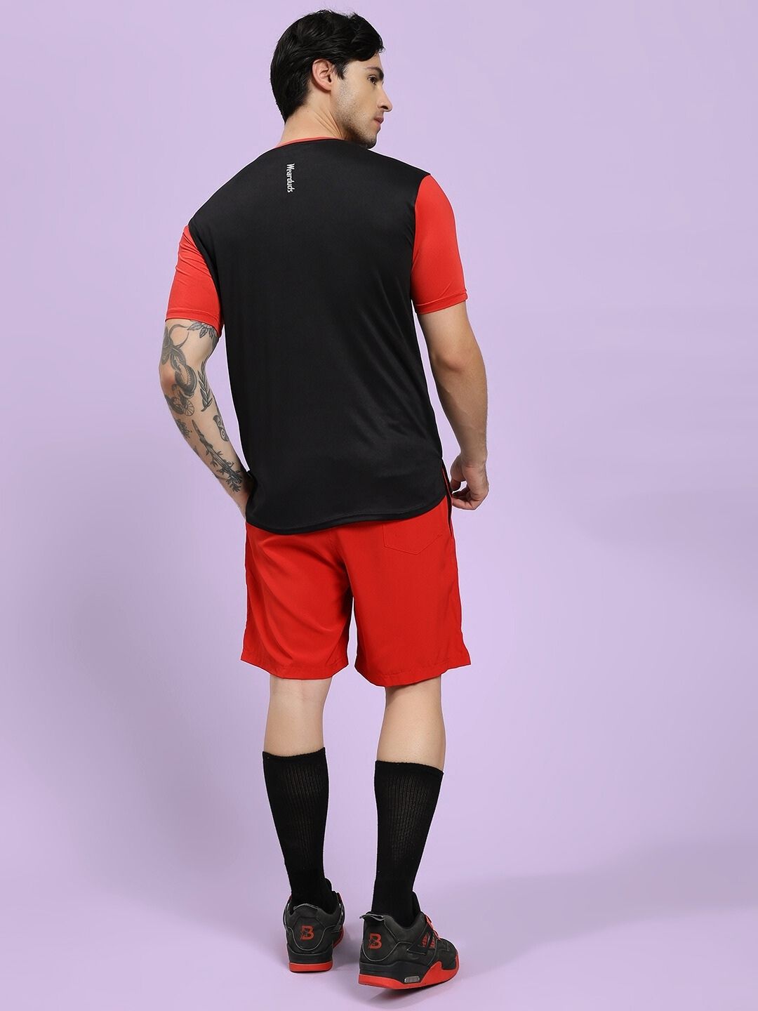 Person wearing a black and red sports outfit on a light purple background