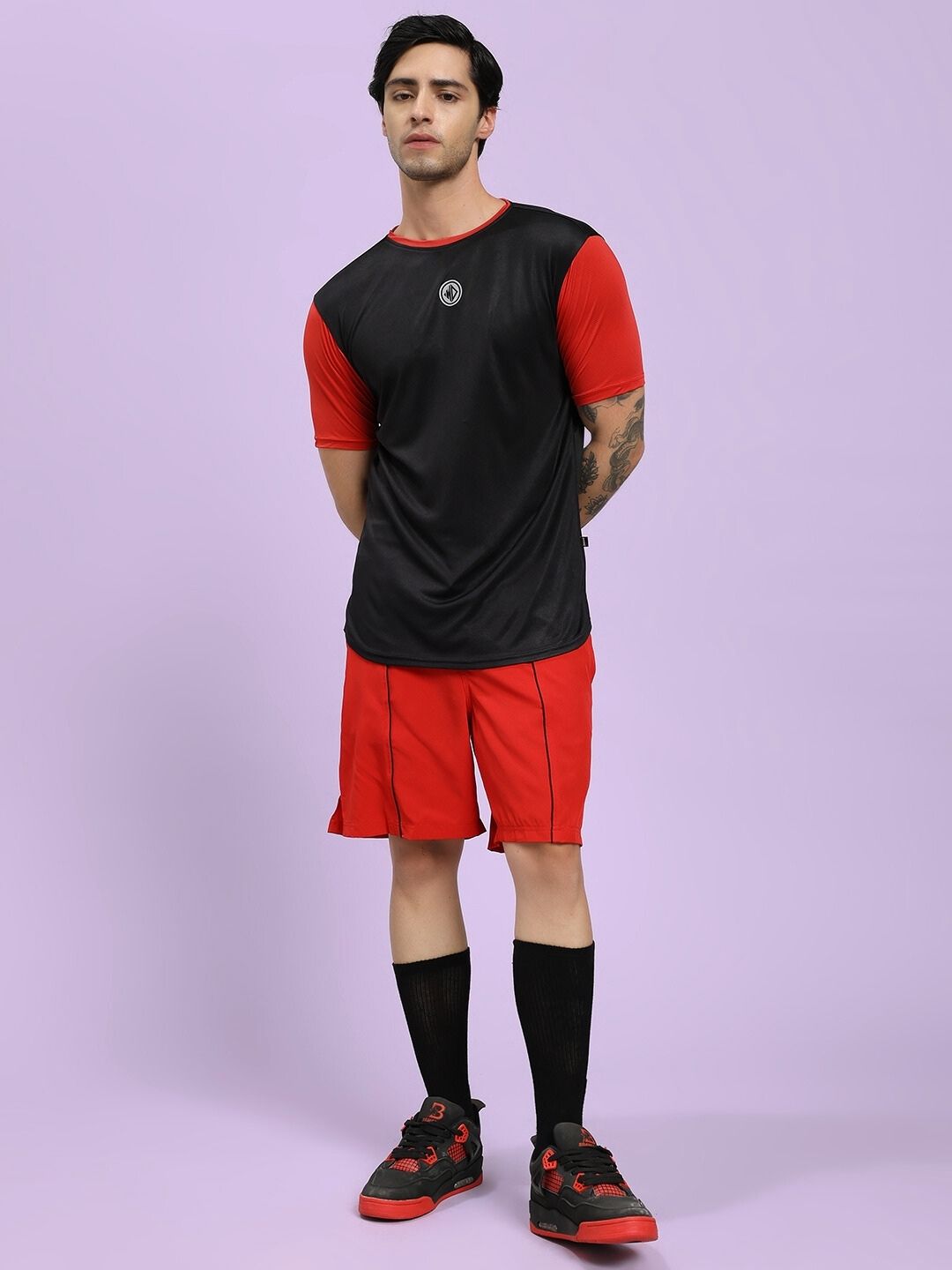 Person wearing a black and red athletic outfit on a light purple background