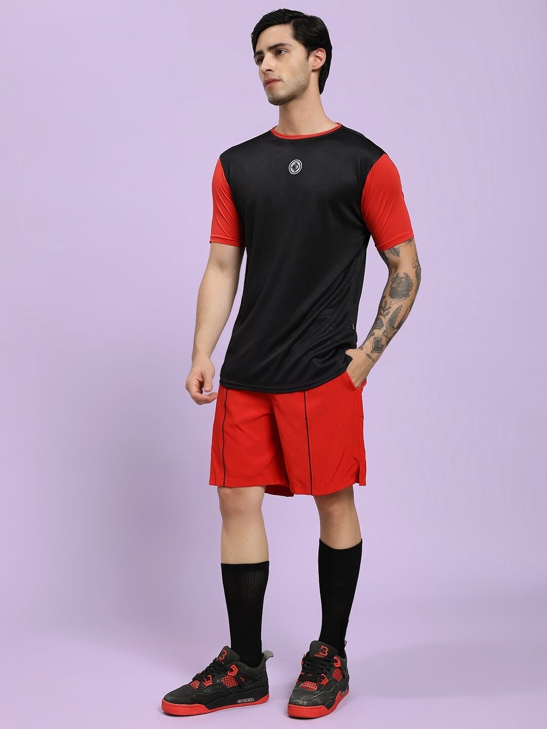 Person wearing a black and red sports outfit on a light purple background