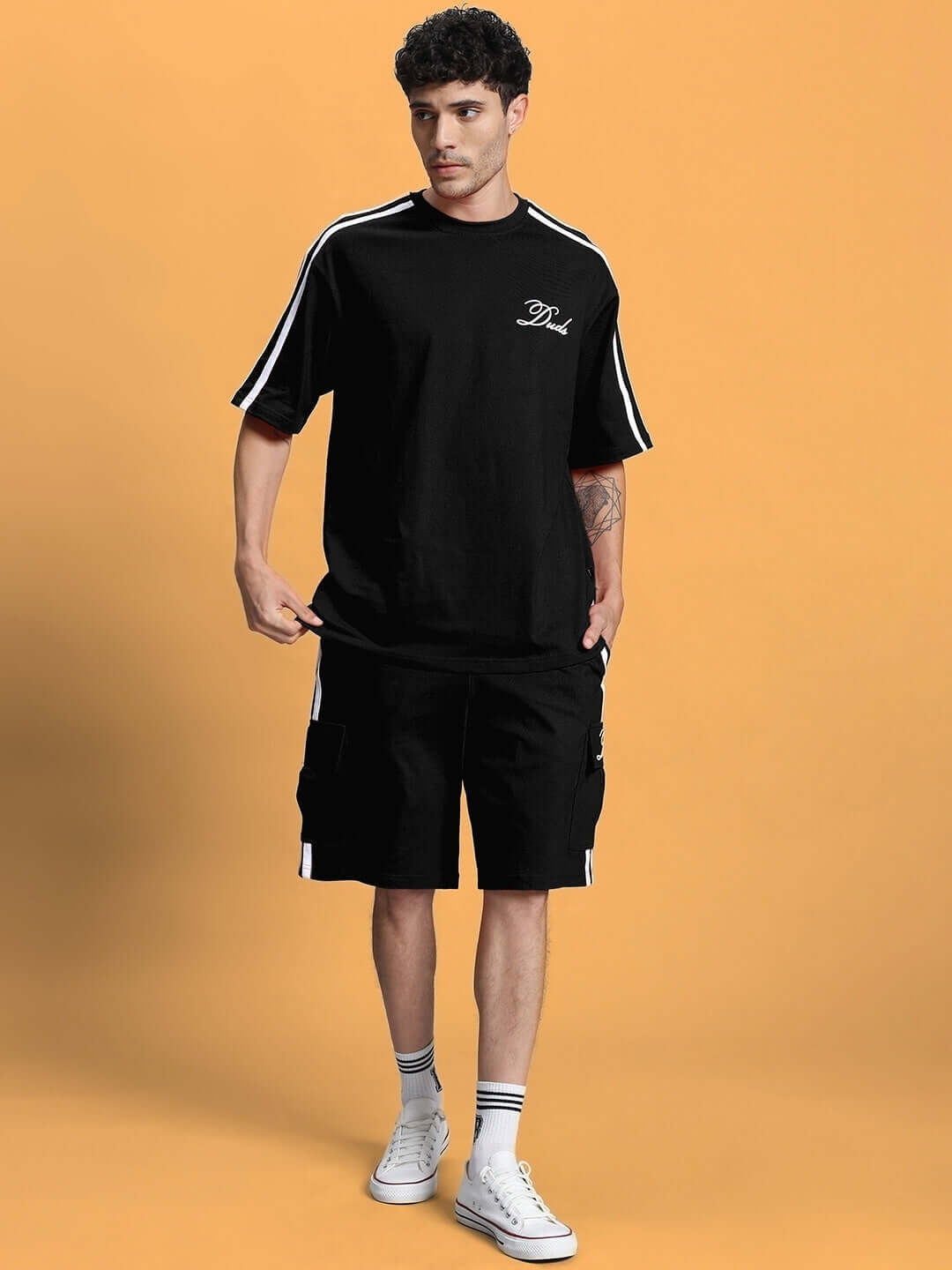 Man wearing SCOTIA Regular Fit Black Shorts and matching top with white sneakers, featuring customizable size options for a tailored fit.
