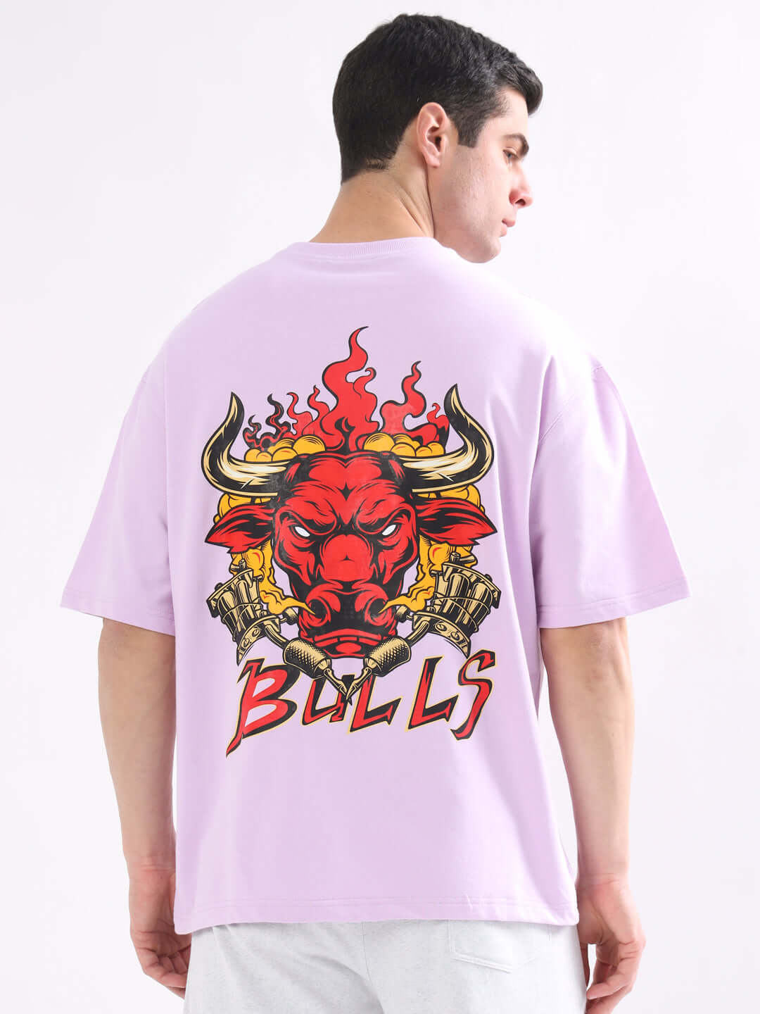 Man wearing WILD BULL OVER-SIZED T-SHIRT LAVENDER with bold graphic on the back, showcasing a trendy streetwear style.