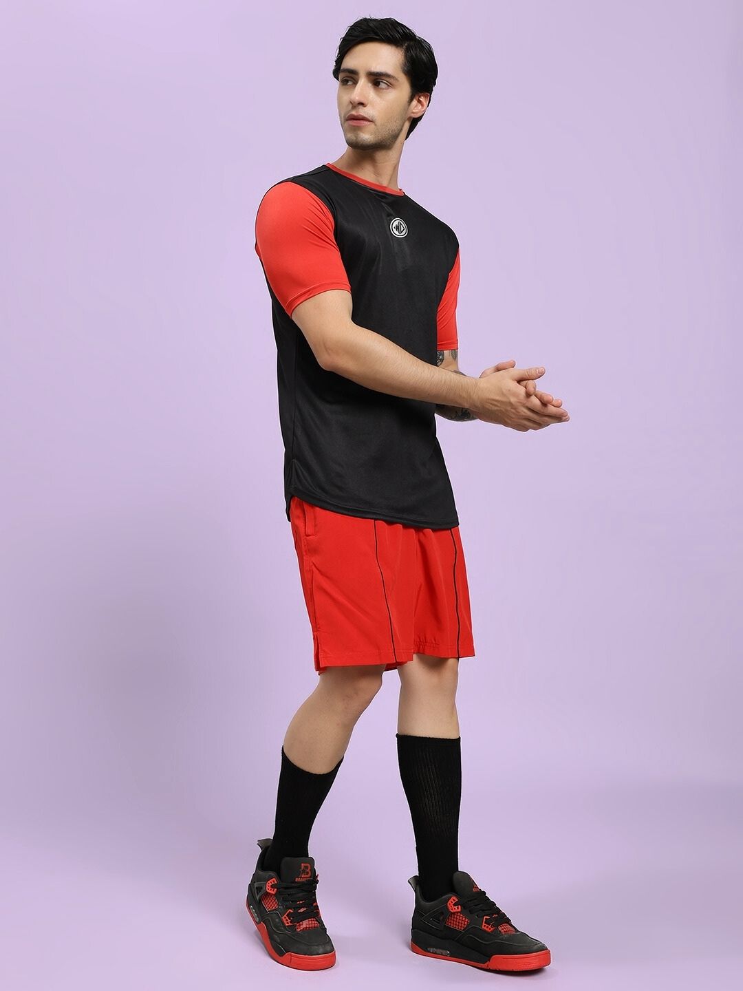 Person wearing a black and red sports outfit on a light purple background