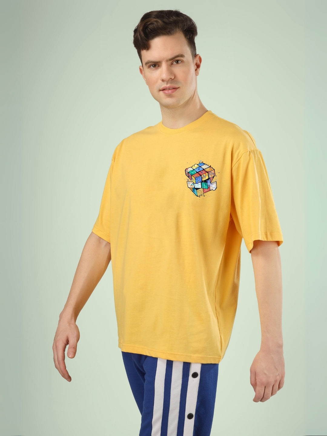 RUBIK REVOLUTION OVERSIZED T-SHIRT YELLOW, casual look, man wearing yellow t-shirt with cube design, customizable size option available.