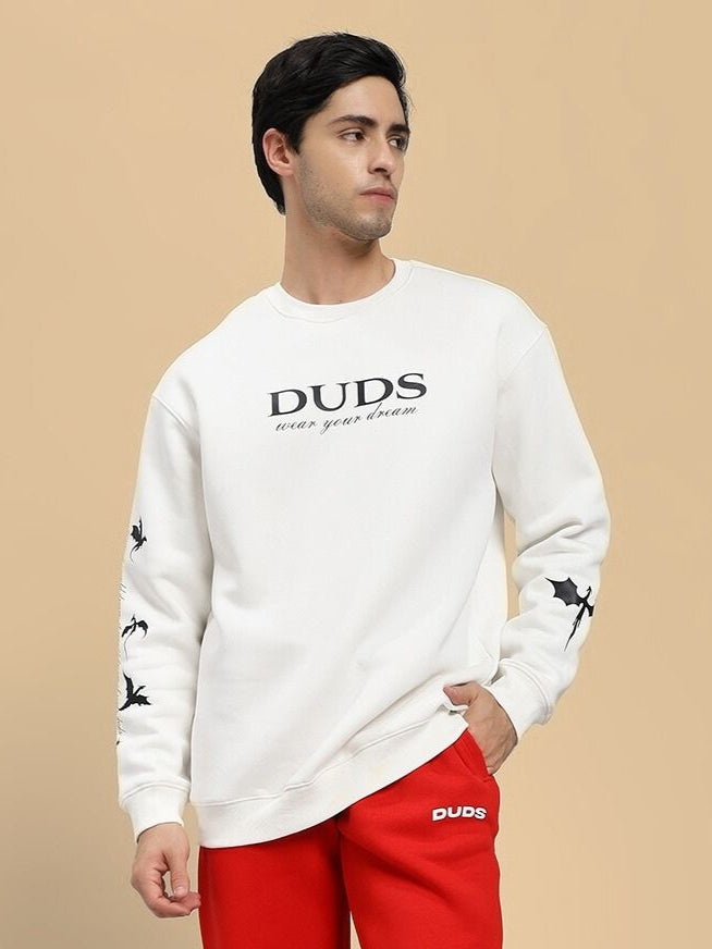Man wearing a white sweatshirt with 'DUDS' branding on a beige background