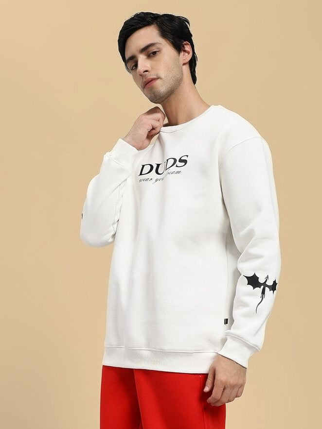 Man wearing a white sweatshirt with text and red pants on a beige background