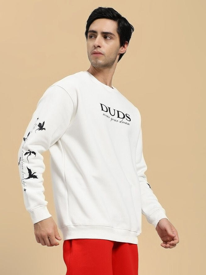 Man wearing a white sweatshirt with 'DUDS' branding on a beige background