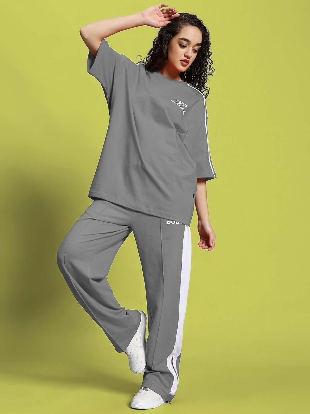 Woman wearing grey-white Wonder Slit Zipper Joggers with matching top from DUDS, showcasing casual fashion style.
