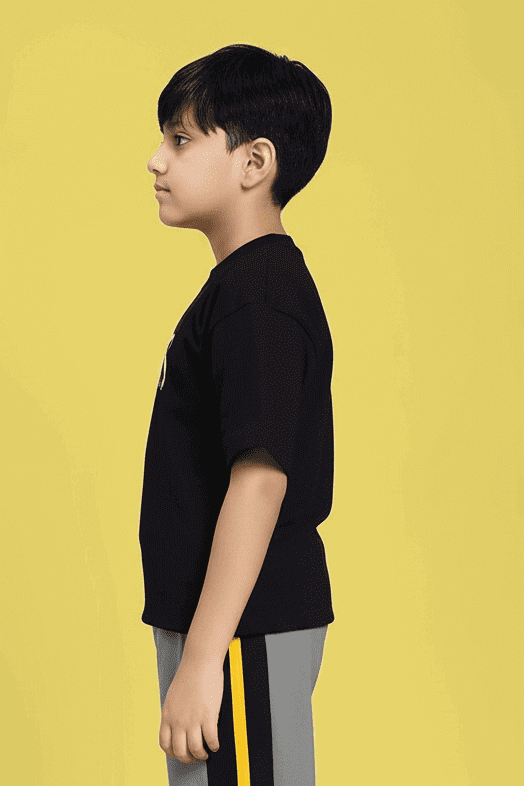 Side view of boy wearing MINING THE MOONLIGHT PRINT T-SHIRT FOR BOYS AND GIRLS BLACK against yellow background, showcasing design.