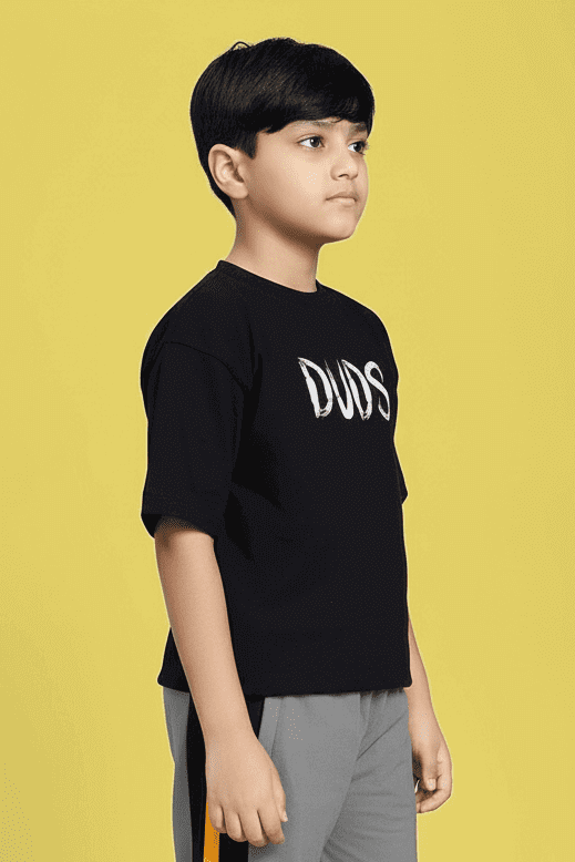 Young boy wearing MINING THE MOONLIGHT PRINT T-SHIRT FOR BOYS AND GIRLS BLACK against a yellow background.