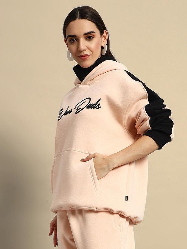 Women's beige-black fleece hoodie, with side pockets and black sleeve accents, styled for casual comfort.