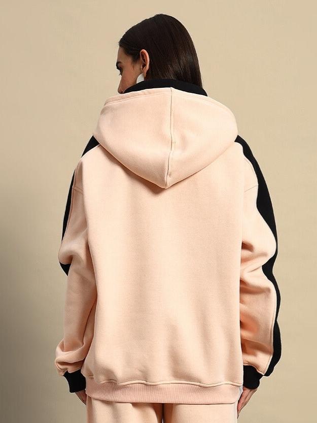 Back view of women's regiment fleece hoodie in beige-black, featuring a cozy hood and contrasting sleeves.