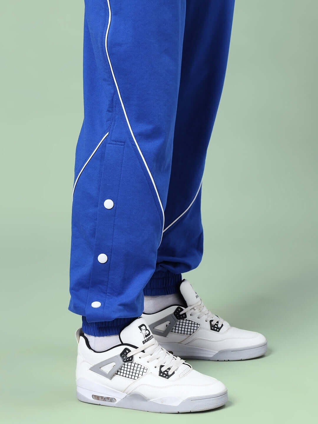 Close-up of Kickshaw relaxed fit blue joggers with white sneakers; features elasticated waistband and drawstring.