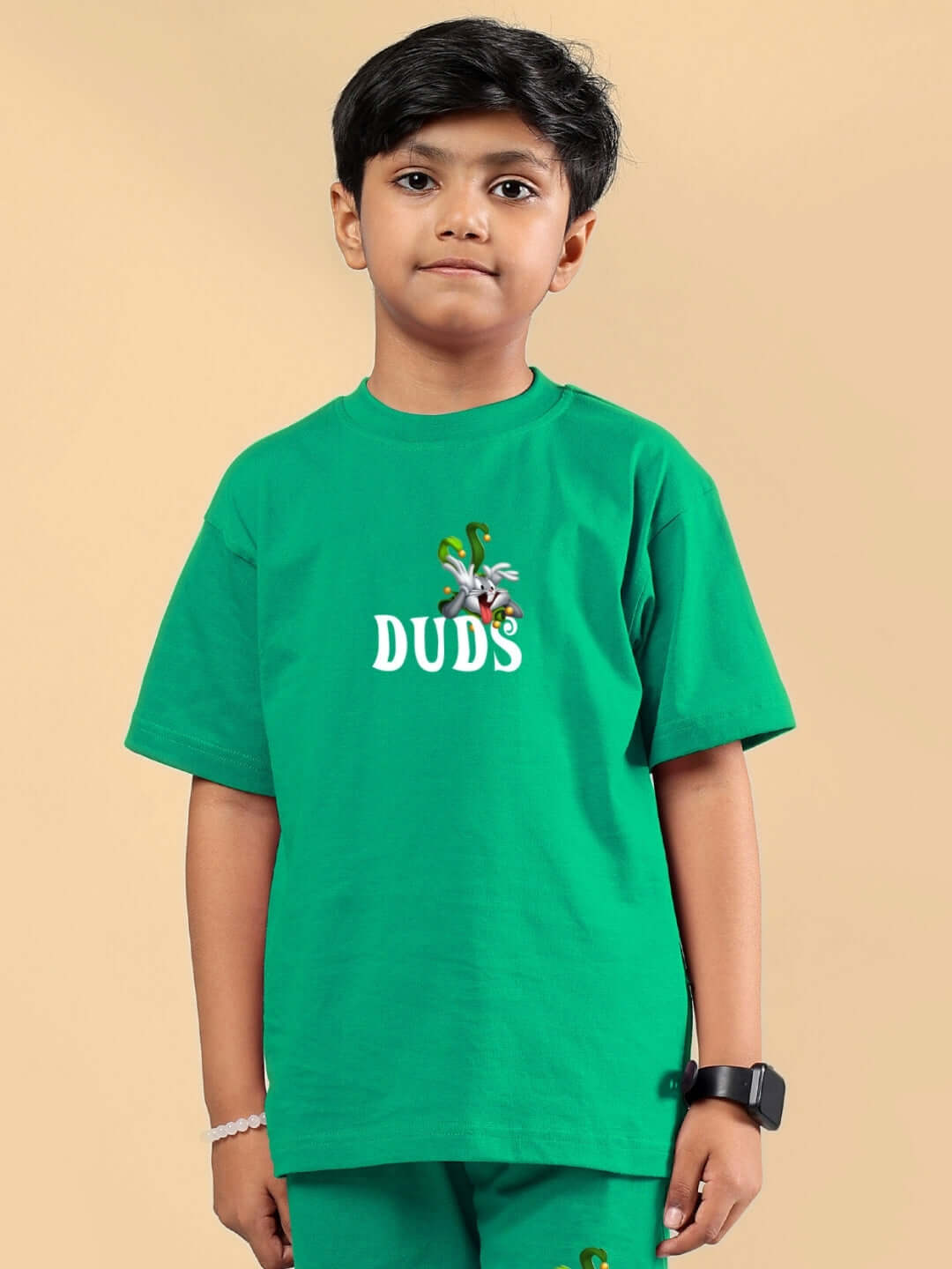 Child wearing a green Looney Tunes printed T-shirt for boys and girls by DUDS, showcasing vibrant cartoon graphics.