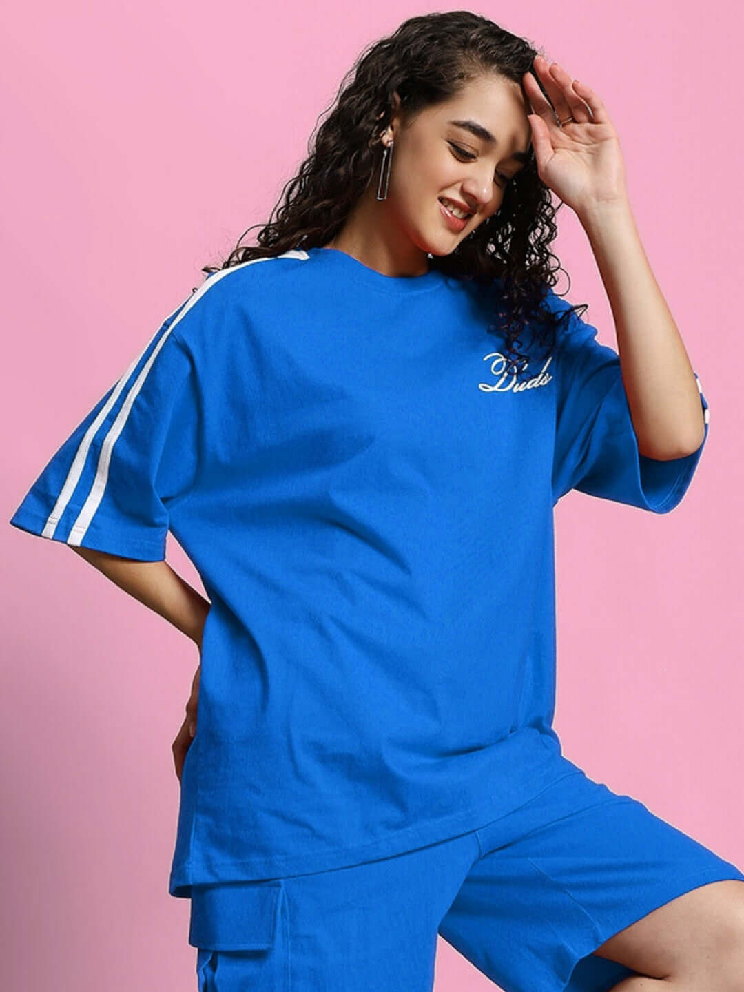 Woman wearing oversized blue t-shirt made of premium cotton French terry, with white stripes, showcasing stylish casual wear.
