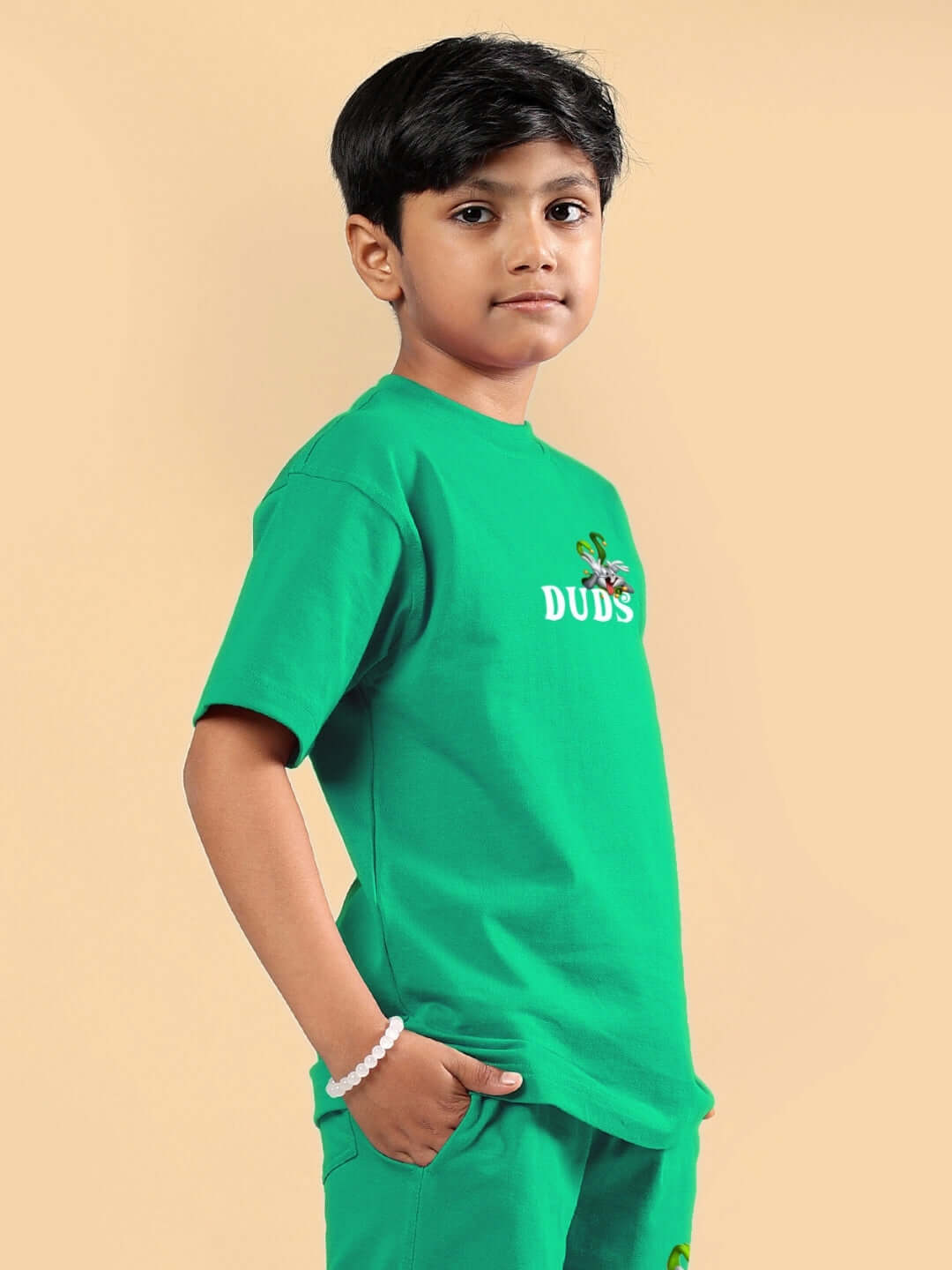 Young boy wearing green Looney Tunes printed T-shirt by DUDS, showcasing colorful cartoon design. Ideal for boys and girls. Custom fit available.