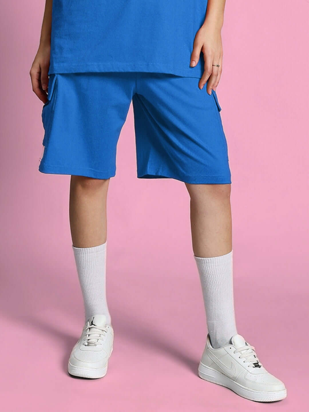 Women's Scotia Regular Fit Blue Shorts with custom fit option, styled with white sneakers and socks on a pink background.