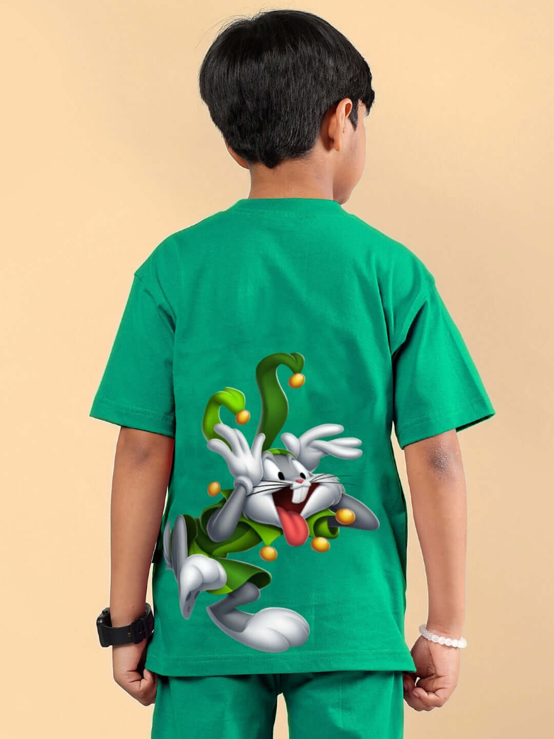 Boy wearing green Looney Tunes printed t-shirt with playful character design on back.