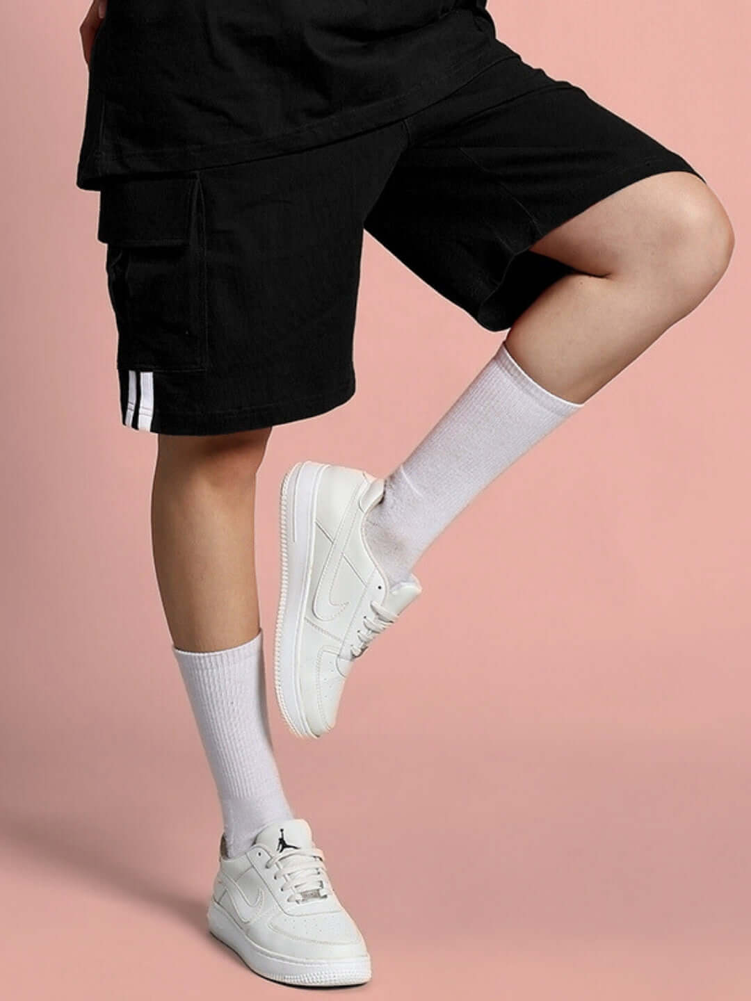 Woman wearing black regular fit shorts with white sneakers, showcasing customizable fit option by DUDS.