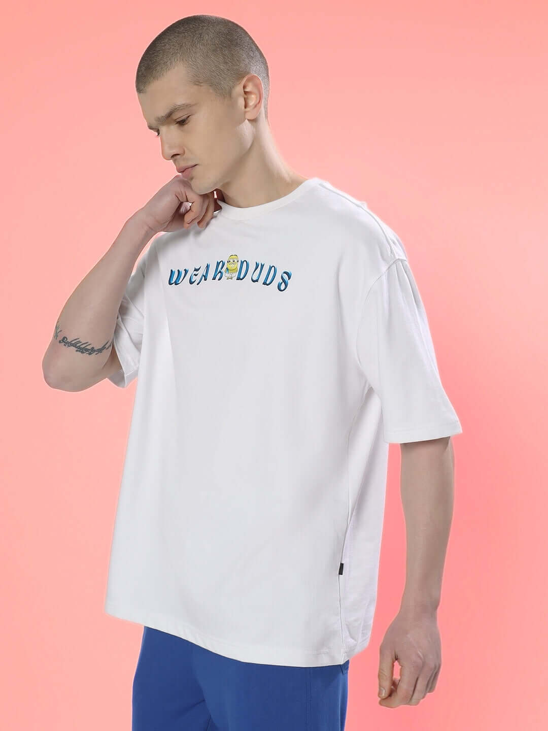 Man wearing SUBRAMIN MINION OVER-SIZED T-SHIRT WHITE with premium heavy gauge fabric on pink background.