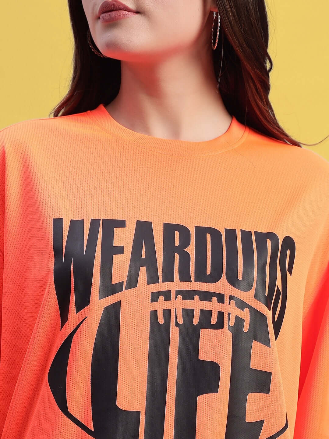 Woman wearing an oversized orange t-shirt with bold black text design.