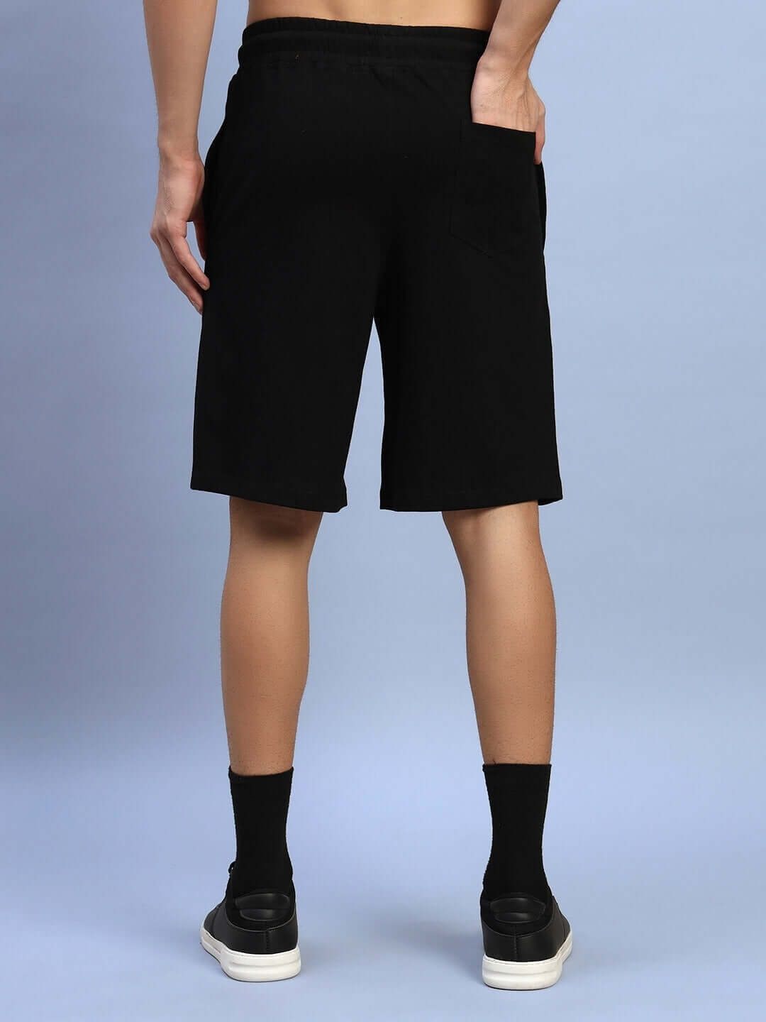 Back view of AMIGA regular fit black shorts, ideal for custom size options and casual wear, shown on a model against a blue background.