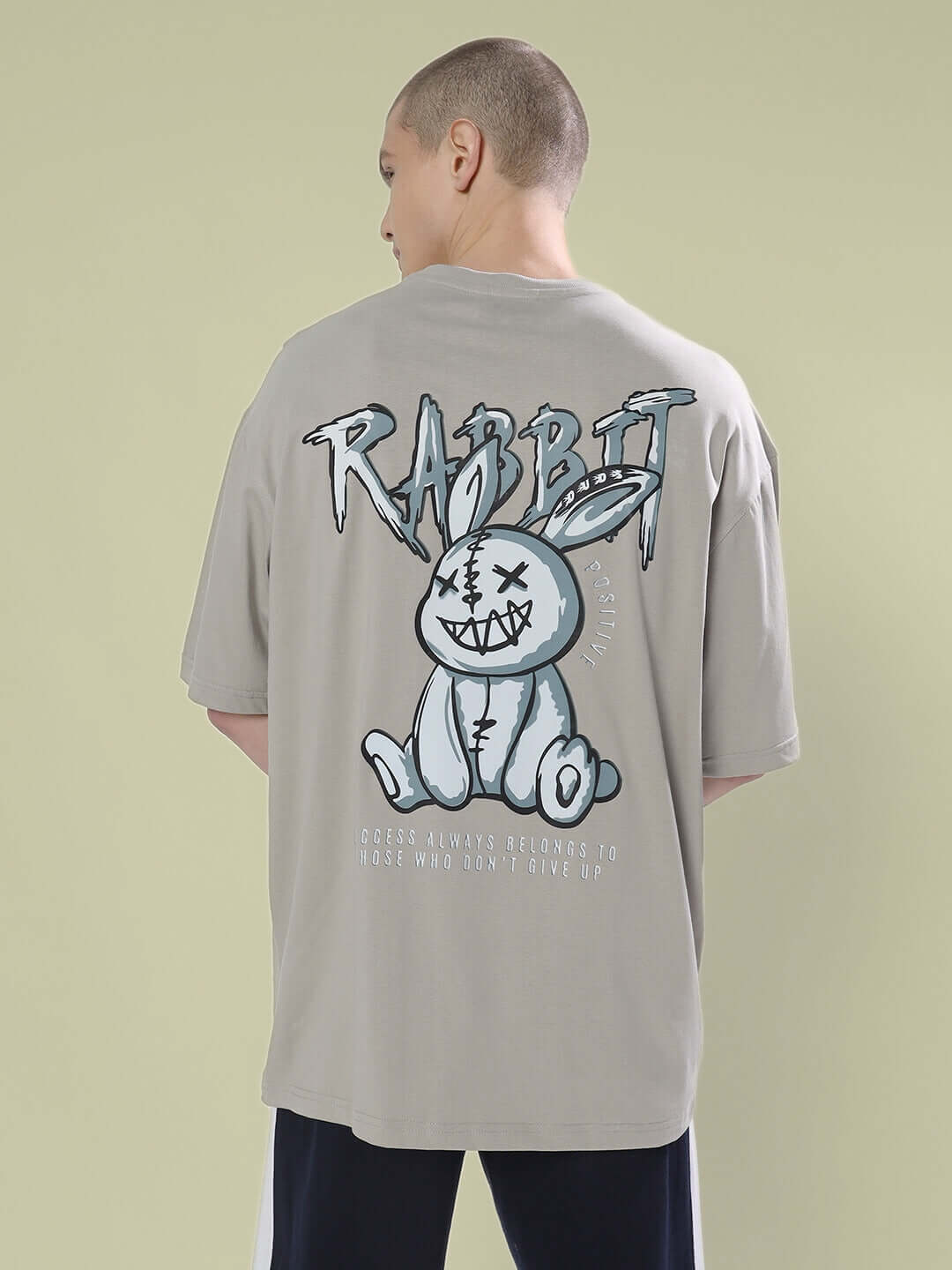Person wearing POSITIVE RABBIT OVER-SIZED T-SHIRT GREY with graphic of a rabbit on the back, made from premium heavy gauge fabric.