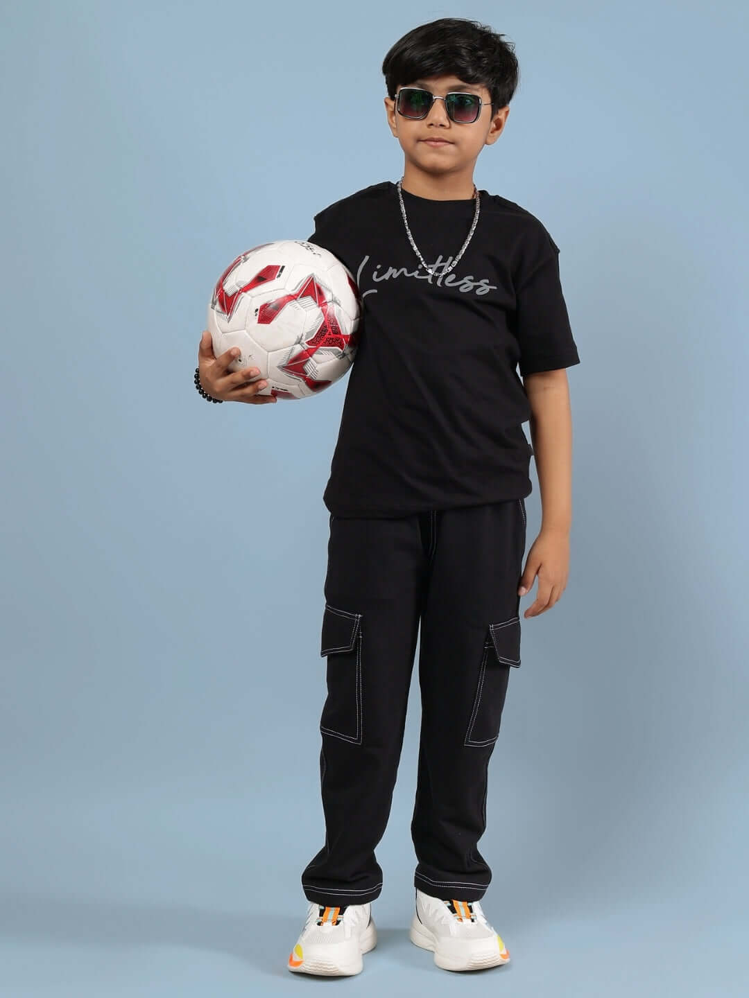Child wearing a black Limitless t-shirt holding a soccer ball, showcasing stylish and comfortable clothing for boys and girls.