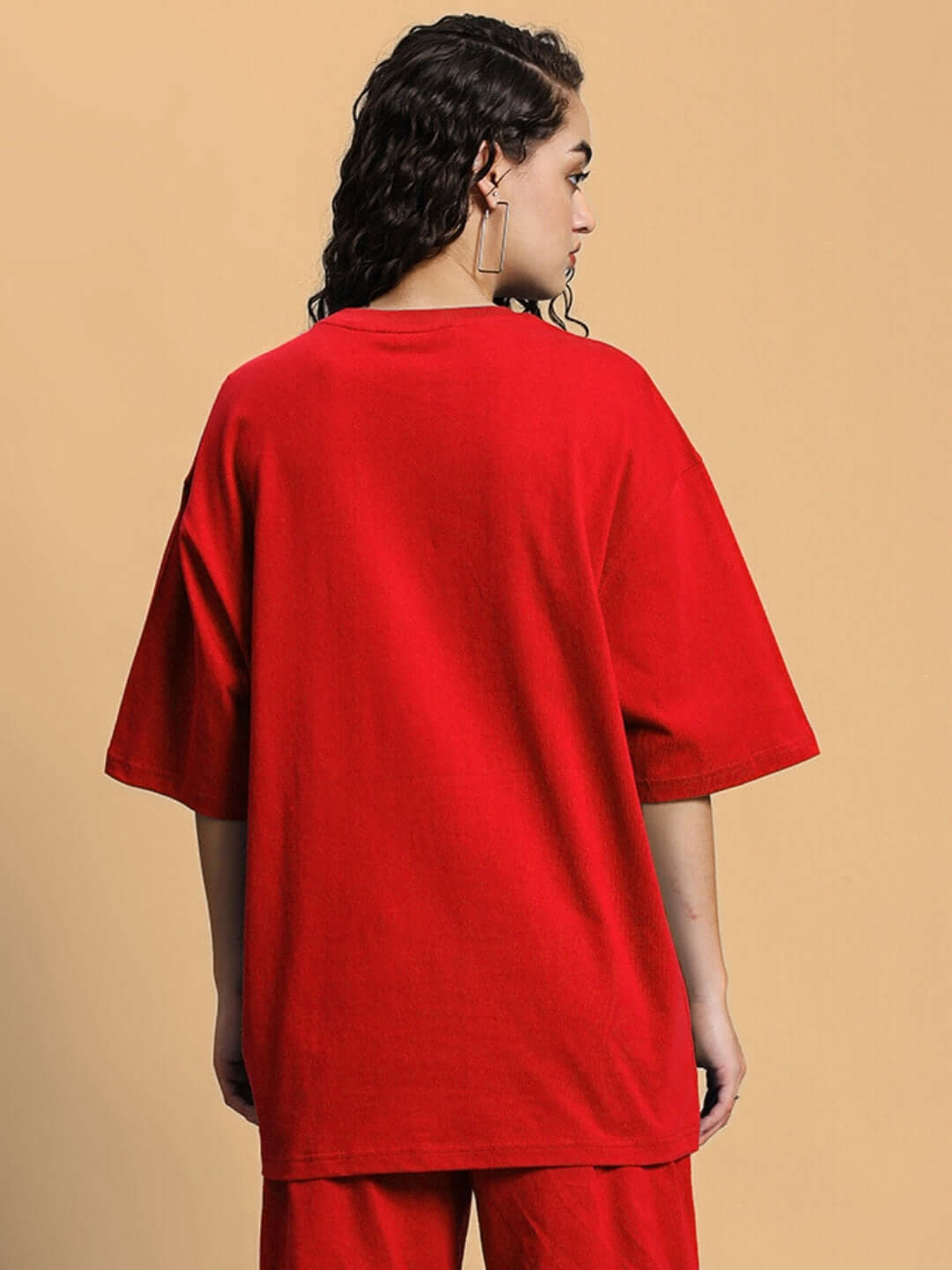 Back view of a woman wearing an oversized red women's T-shirt made of premium cotton fabric, showcasing casual style and comfort.