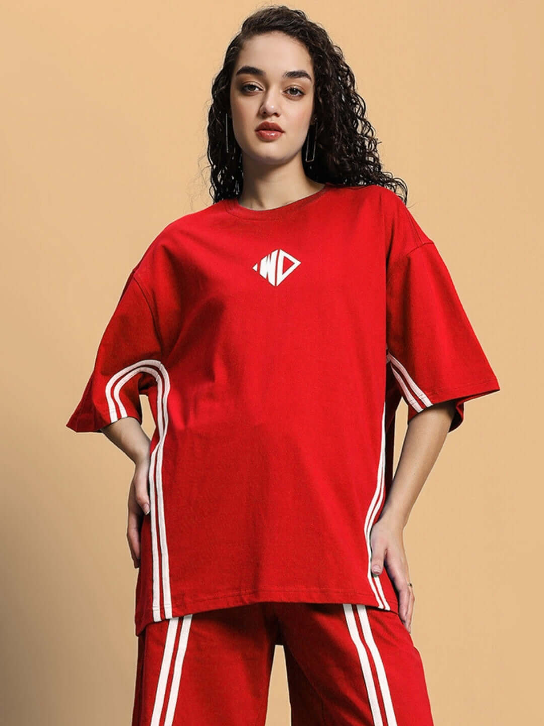Woman wearing a red oversized t-shirt made from premium cotton, featuring white stripes and logo, perfect for casual wear.
