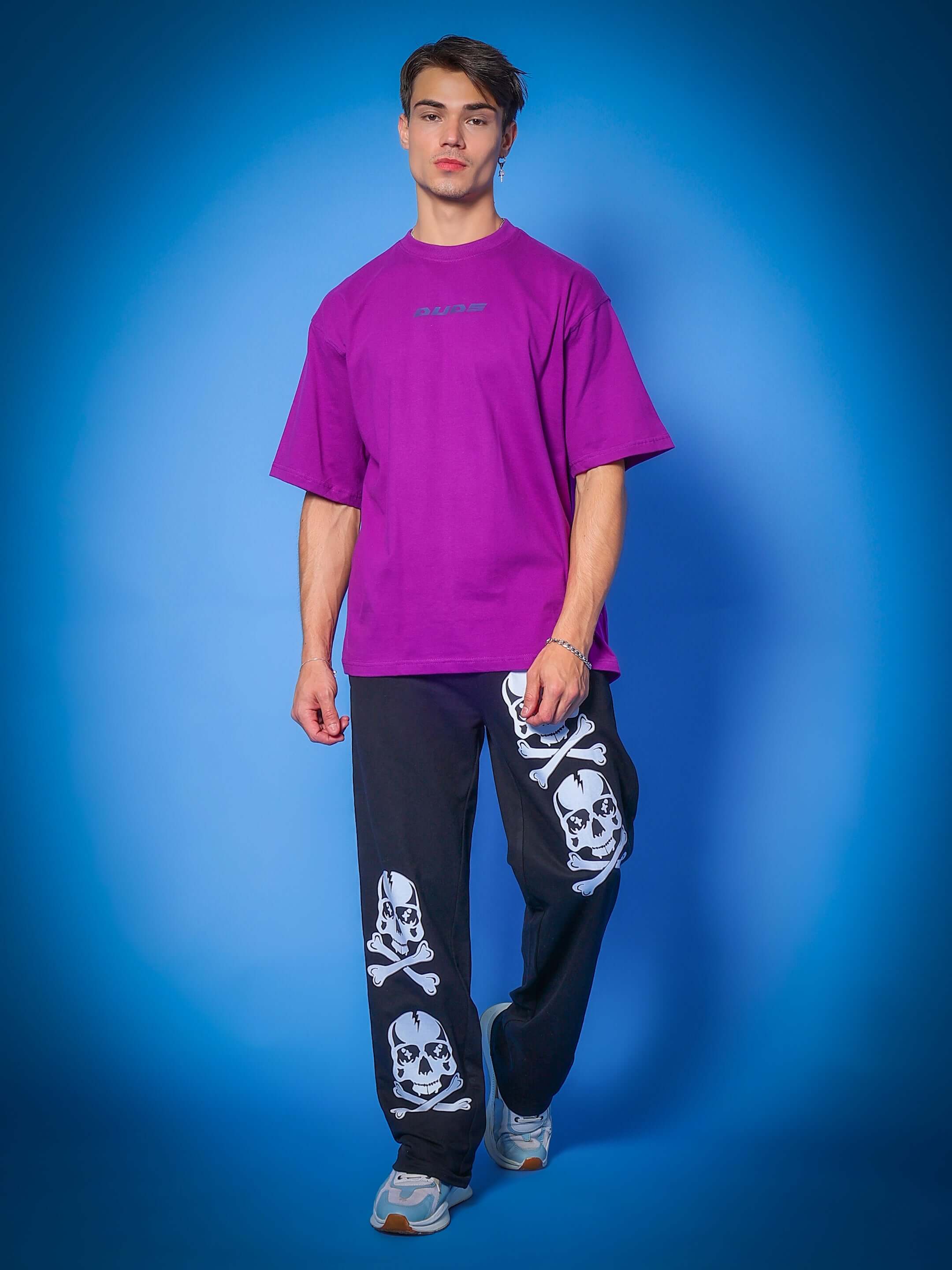 Model wearing the INTERTWINED SNAKE REFLECTOR OVER-SIZED T-SHIRT PURPLE against blue background