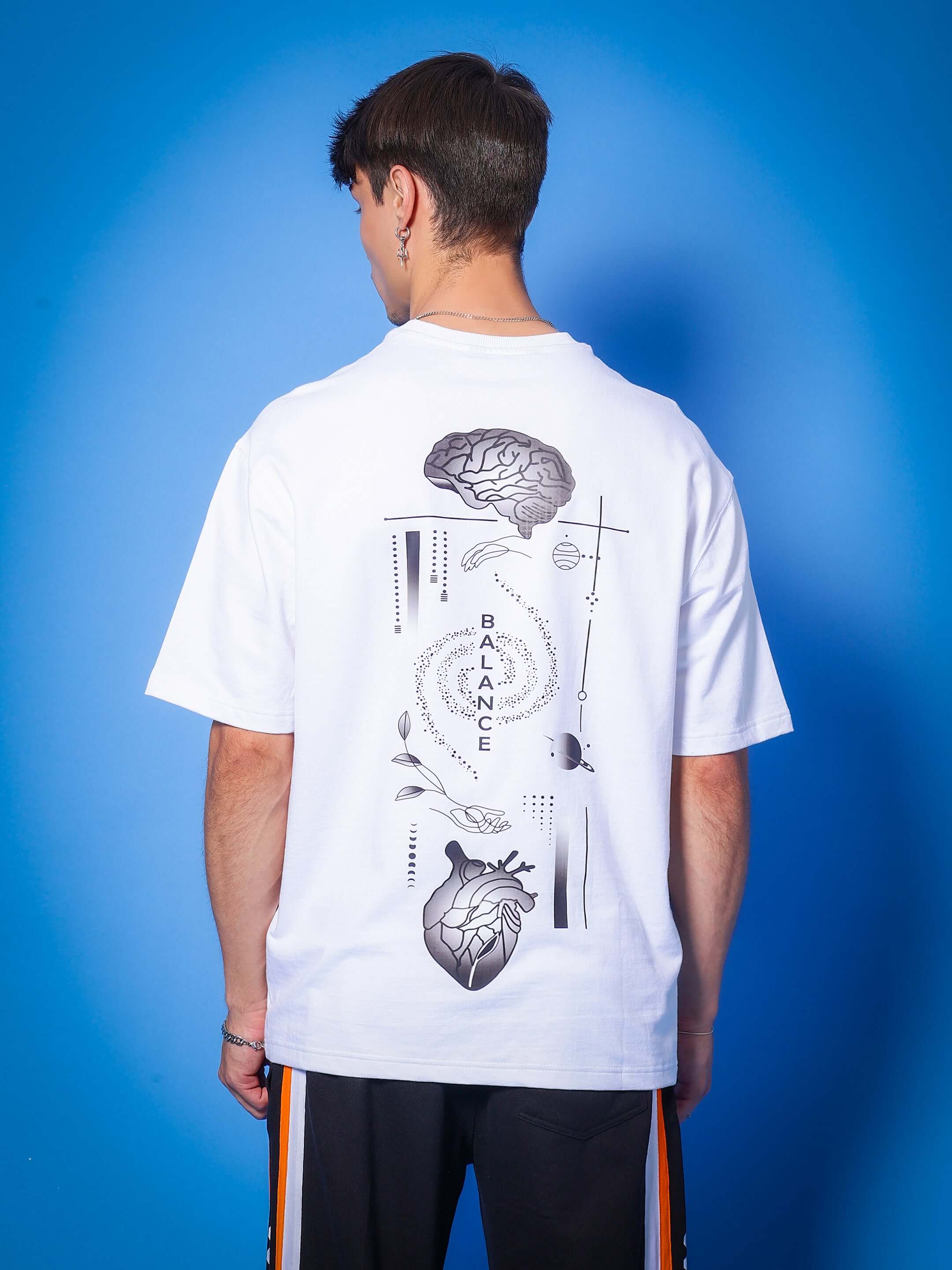 Model wearing MIND & SPIRIT GOTHIC ART PRINT OVER-SIZED T-SHIRT WHITE with back design, against blue background.