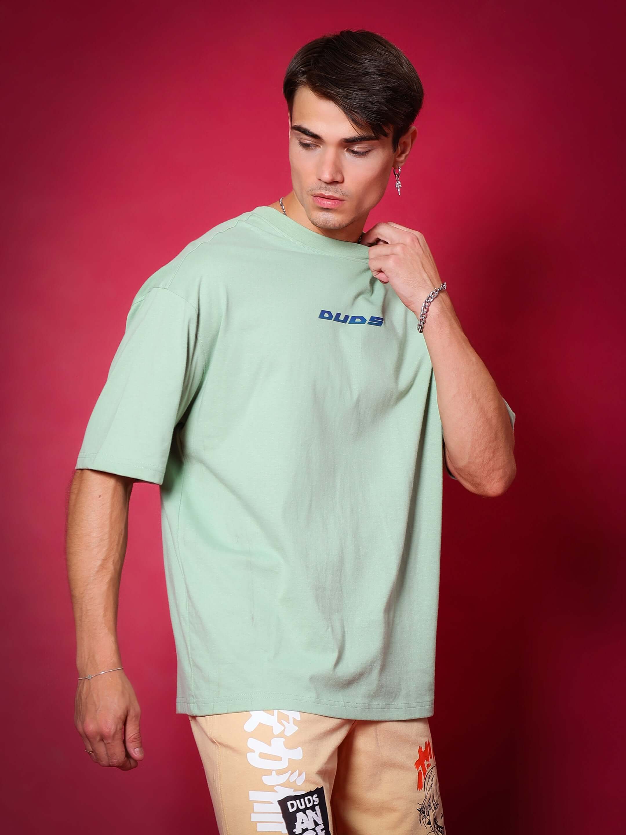 Men wearing PRAY OVER-SIZED T-SHIRT NYANZA GREEN made of premium heavy gauge fabric, 97% cotton and 3% elastane, shown on red background