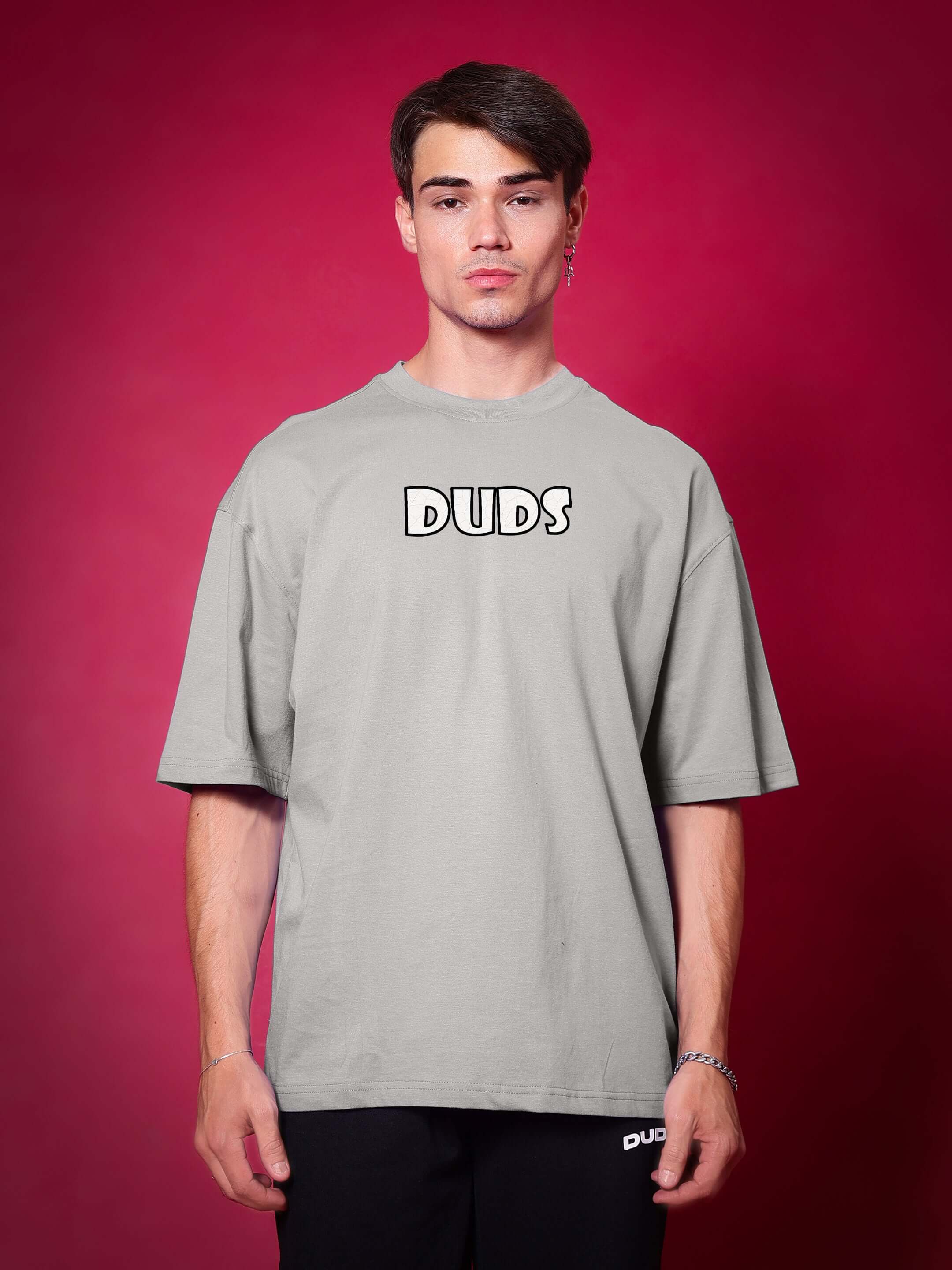 Model wearing WOLF PACK OVER-SIZED T-SHIRT GREY with a bold, laid-back style against a red background.