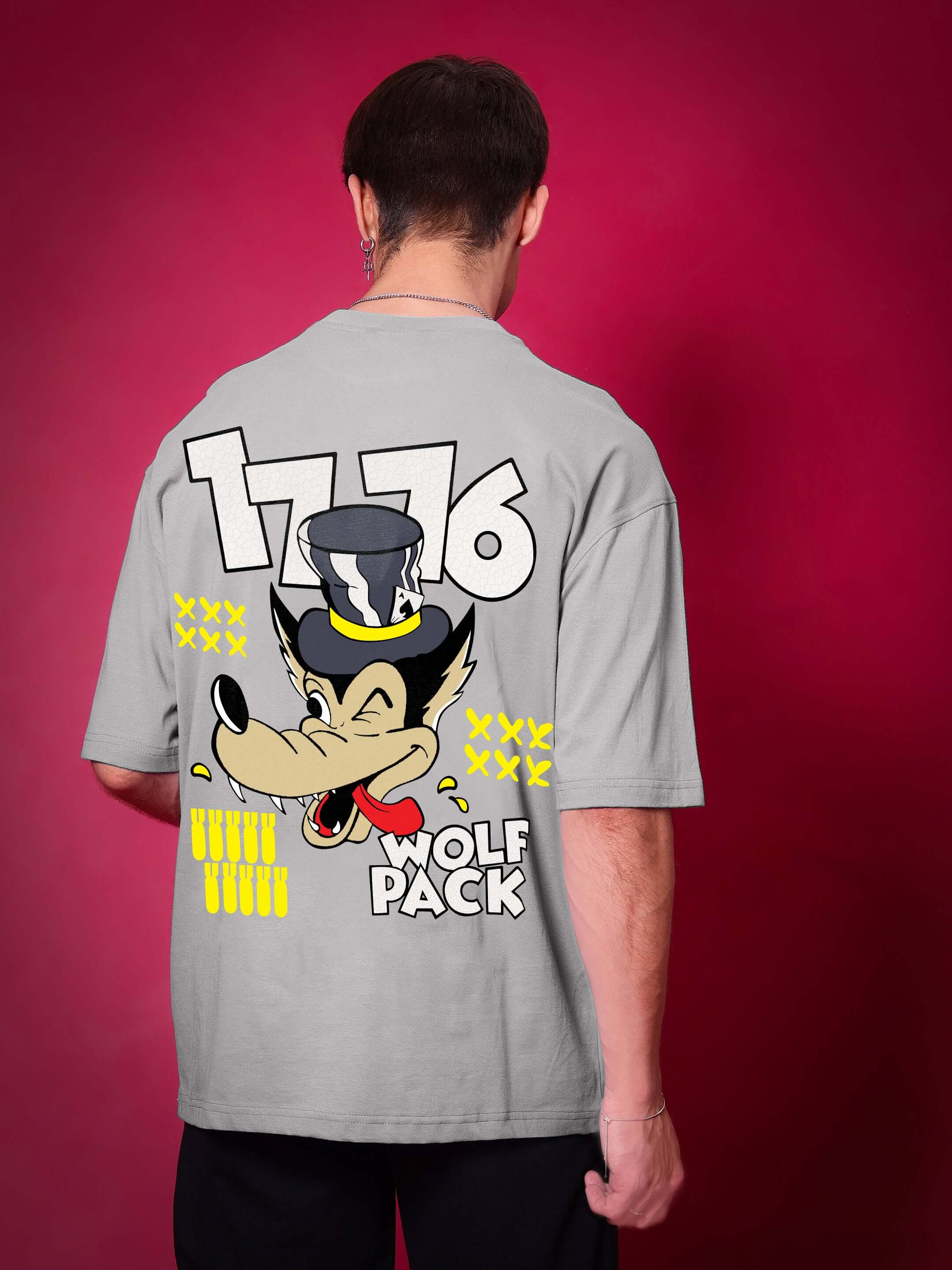 Back view of person wearing WOLF PACK OVER-SIZED T-SHIRT GREY with graphic design on red background.