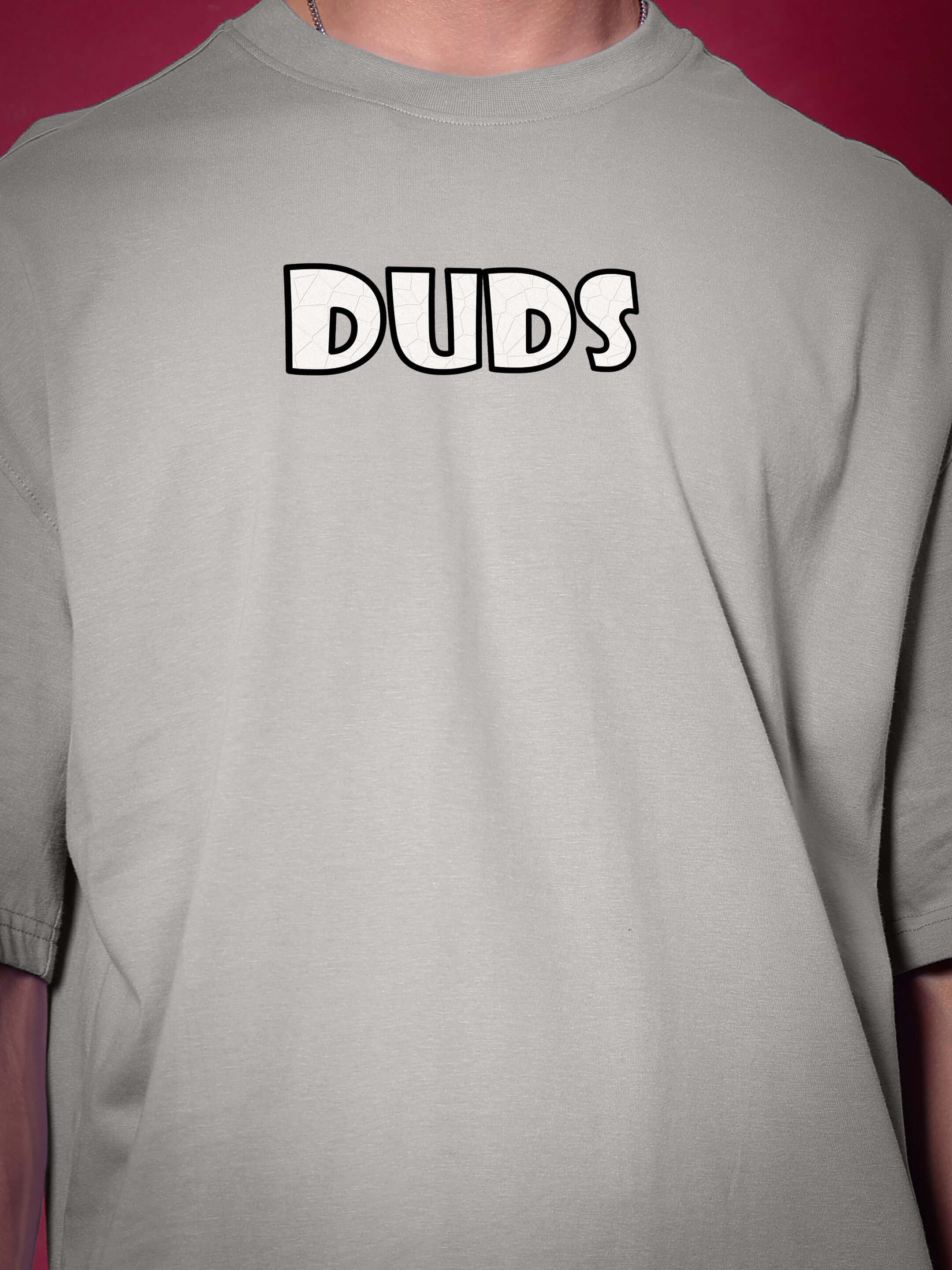 Person wearing WOLF PACK OVER-SIZED T-SHIRT GREY displaying "DUDS" text on front