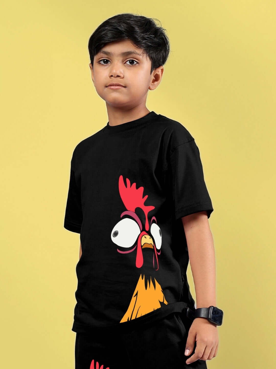 Child wearing black funny chicken printed T-shirt for boys and girls, designed by DUDS, showcasing a playful rooster graphic on yellow background.