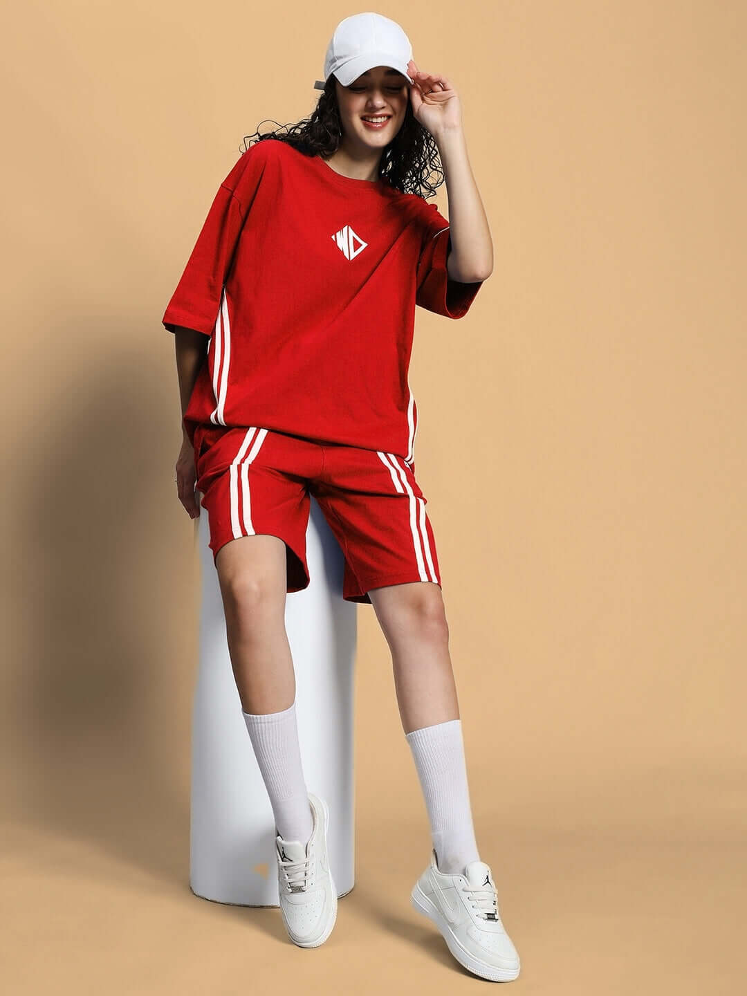 Woman wearing red women's shorts and matching top, smiling with cap and sneakers, showcasing DUDS Regular Fit Shorts.
