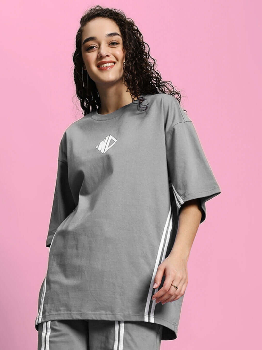 Model wearing grey oversized women's T-shirt made of premium cotton blend, featuring a relaxed fit and stylish design.