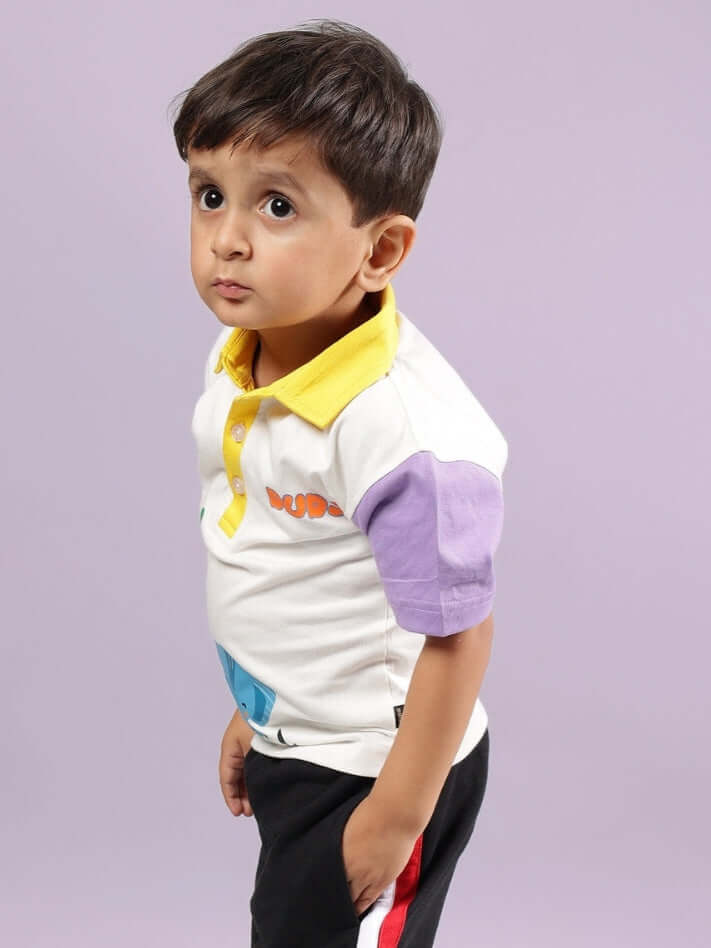 Young child wearing a colorful collared t-shirt, standing against a plain background, showcasing off-white fabric with purple and yellow accents.