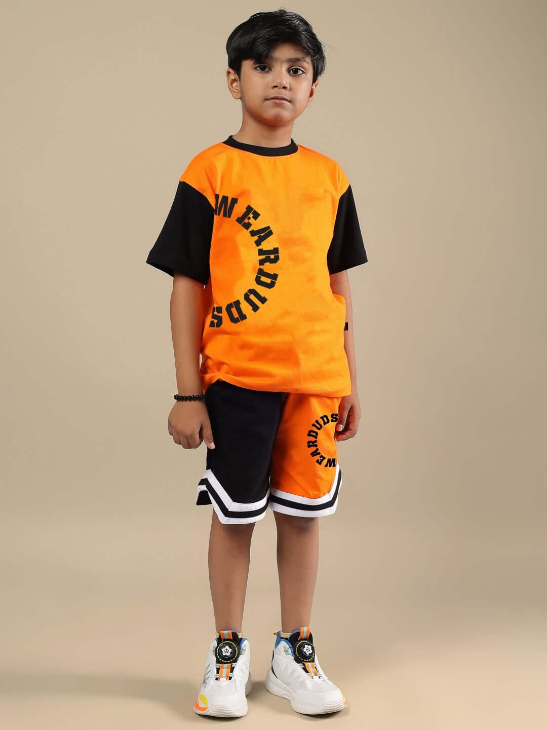Child wearing black and orange track and field shorts and matching shirt, featuring sporty design by DUDS.