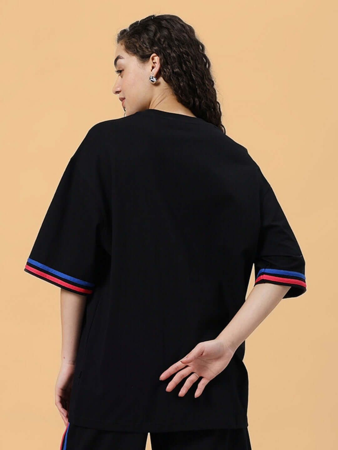 Back view of a woman wearing a Women's Miami oversized black T-shirt with red and blue striped sleeves, made of premium cotton French terry.