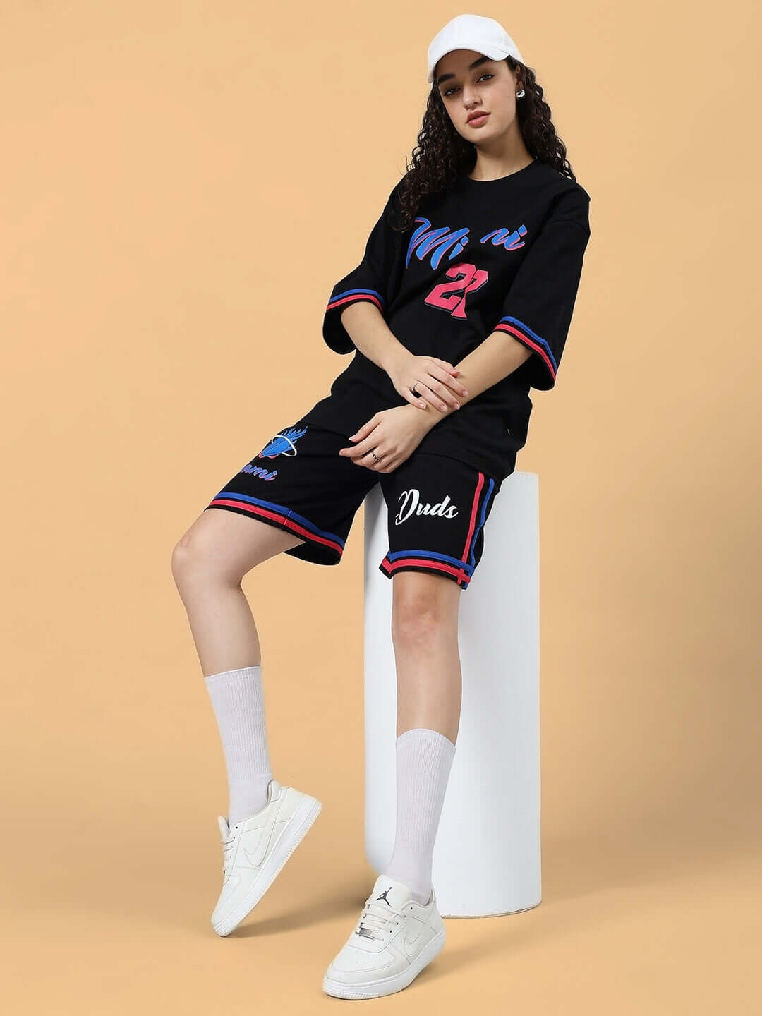 Woman wearing black Miami regular fit shorts with custom fit option, seated with casual style. DUDS customization available.