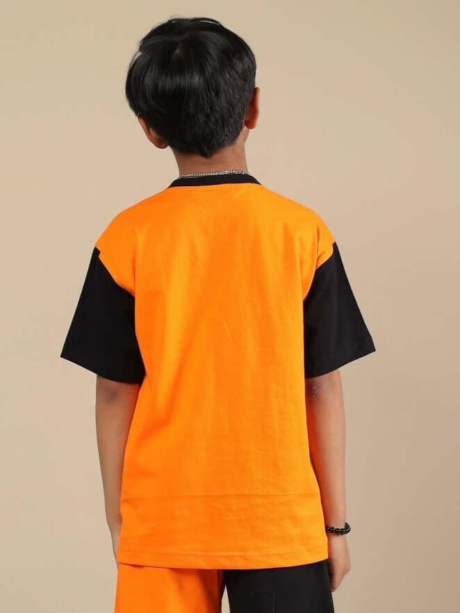 Back view of a child wearing a TRACK & FIELD T-shirt for boys and girls, featuring a black and orange design.